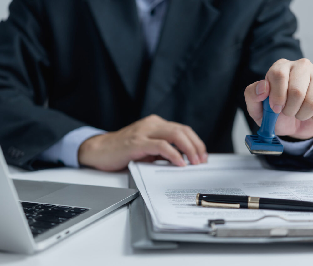 Man stamping approval of work finance banking or investment marketing documents on desk.